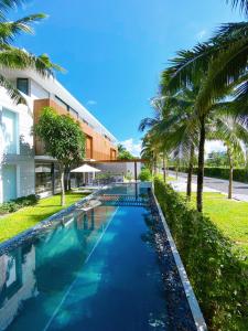 a swimming pool in front of a building with palm trees at Phoenix Pool Villa Phu Quoc in Phu Quoc