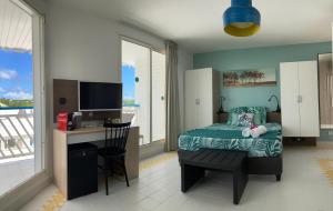 une chambre avec un lit et un bureau avec une télévision dans l'établissement GRAND TI-BOU Gwada breizh, à Saint-François