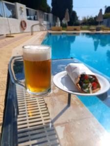 a glass of beer and a plate of food next to a pool at Casa Blue Sarantis in Faliraki