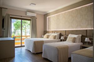 um quarto de hotel com duas camas e uma varanda em Hotel Pousada Kaster em Gramado