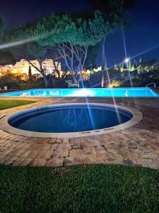 a pool with lights in a park at night at Vieira apartment 1 in Quarteira
