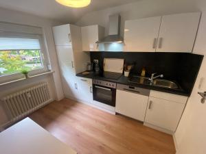 a kitchen with white cabinets and a sink and a window at Apartments-Badharzburg / Ferienwohnung im Zentrum in Bad Harzburg