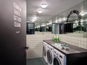 a laundry room with a washing machine and a mirror at STAYERY Cologne Ehrenfeld - Live Music Hall in Cologne