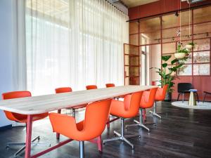 einen Konferenzraum mit einem langen Tisch und orangefarbenen Stühlen in der Unterkunft STAYERY Köln Ehrenfeld in Köln