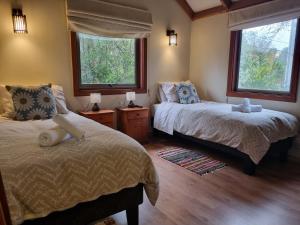 a bedroom with two beds and two windows at Hostel Torobayo in Valdivia