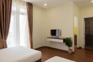 um quarto com uma cama, uma televisão e uma janela em Dalat Blanc Hotel & Apartment em Da Thanh