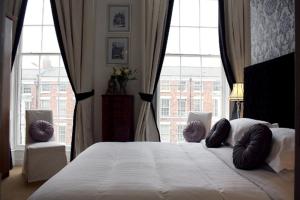 a bedroom with a large white bed with large windows at The Georgian Town House Hotel in Liverpool