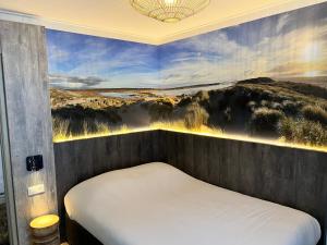 een slaapkamer met een bed met een schilderij aan de muur bij Hotel Nap in West-Terschelling