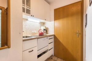 cocina con armarios blancos y puerta de madera en Fellhornblick en Reit im Winkl