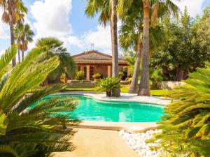 una piscina frente a una casa con palmeras en Can Suau, en Llubí