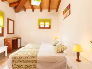 ein weißes Schlafzimmer mit einem Bett, einem Schreibtisch und einer Lampe in der Unterkunft Can Suau in Llubí