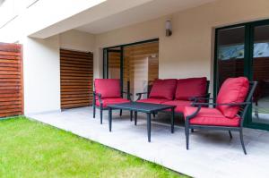 a patio with red chairs and a table at BG LUXIMMO APARTMENTS in Cluj-Napoca