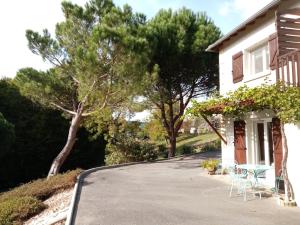 a driveway leading to a house with chairs and trees at Chambre calme en correze in Sainte-Fortunade