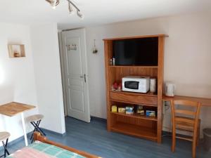 a room with a television and a microwave on a shelf at Chambre calme en correze in Sainte-Fortunade