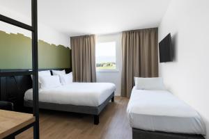 ein Hotelzimmer mit 2 Betten und einem Fenster in der Unterkunft B&B HOTEL Geneva Airport in Genf