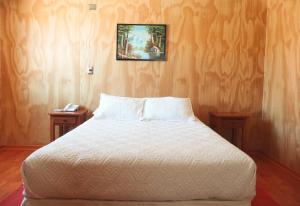 a bedroom with a white bed with two night stands at Hotel Iorana Tolache in San Pedro de Atacama