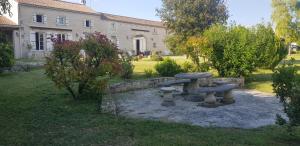 a stone bench in a yard with a building at La Revêtizon in Siecq
