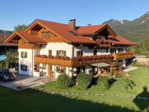Una casa grande con un balcón con flores. en Ferienwohnungen Anton Geierstanger, en Wallgau