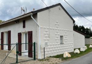 Gîte Le petit quartier في Berson: مبنى ابيض امامه سياج
