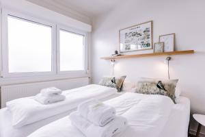 twee witte bedden in een witte kamer met handdoeken erop bij Hlid Bed and Breakfast in Myvatn