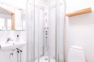 ein weißes Bad mit einer Dusche und einem Waschbecken in der Unterkunft Hlid Bed and Breakfast in Mývatn