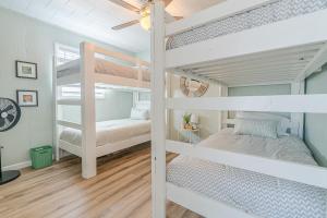 a bedroom with two bunk beds and a ceiling fan at NEW updated home w/ firepit, 2 min walk to beach in Surfside Beach