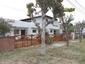 dom z płotem i drzewami przed nim w obiekcie Alojamientos frente al Mar Complejo "El Estar De La Costa" w mieście San Clemente del Tuyú