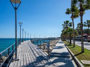 a boardwalk next to the ocean with palm trees at Sanders Aqua Park Resort - Precious 3-Bedroom Holiday Home With Shared Pool in Limassol