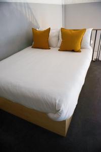 Una gran cama blanca con almohadas amarillas. en Leevin Studios, en Dublín