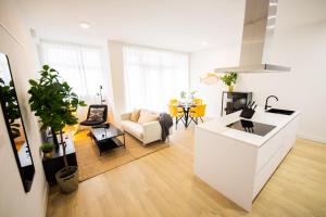 een witte keuken en een woonkamer met een bank en een tafel bij Cheerfully 1 Bedroom Serviced Apartment 52m2 -NB306C- in Rotterdam