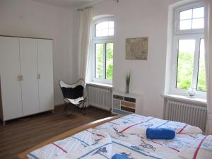 1 dormitorio con 1 cama, 1 silla y ventanas en FeWo UKENA DORN204, en Dornum