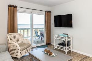 a living room with a couch and a tv and a balcony at CB45 2B at the Beach in Carolina Beach