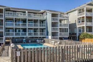 a pool in front of a building with a fence at 2B at the Beach in Carolina Beach