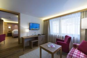 レッヒにあるHotel Garni Panoramaのベッドとリビングルームが備わるホテルルームです。