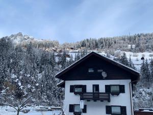 a white house with a black roof in the snow at Chalet Stanzertal in Strengen
