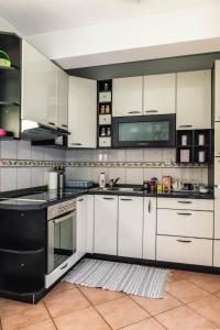 eine Küche mit weißen Schränken und schwarzen Geräten in der Unterkunft Apartman Jana in Bijeljina