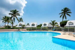 una piscina con palmeras y casas en Modern Beach Villa 1150, en Saint Martin
