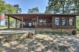 una casa de madera con porche y bandera americana en The Bird Cabin Peaceful Refuge in East Texas, en Ben Wheeler