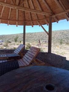 a wooden table and chairs under a wooden roof at Cabañas El Molino in Potrerillos