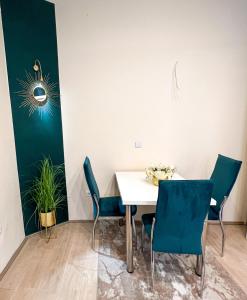 a dining room with a white table and blue chairs at Dis apartman 2 in Kruševac