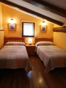 two beds in a room with yellow walls at Casa La Tornagua in Biescas
