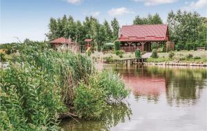 a lake with a building and a picnic table next to it at Beautiful Home In Wegorzewo With 3 Bedrooms, Wifi And Sauna in Trygort