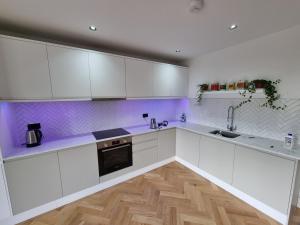 a kitchen with white cabinets and a wooden floor at Bright spacious apartment in the park in London
