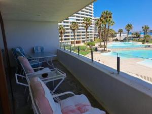 balkon z krzesłami i widokiem na basen w obiekcie Condominio Jardín del Mar w mieście Coquimbo