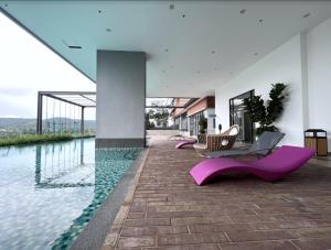 uma casa com cadeiras roxas e uma piscina em FREE PARKING # 2 Bed Family BellSuite - Sepang KLIA Kota Warisan em Sepang