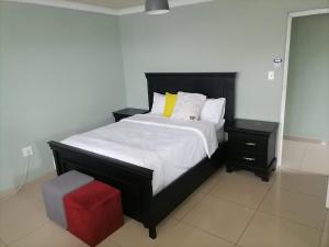 a bedroom with a black bed and a red stool at Queens And Kings Lodge in Durban