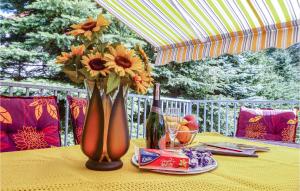 a table with a vase of flowers and a bottle of wine at One-Bedroom Holiday Home In Biskupiec in Biskupiec