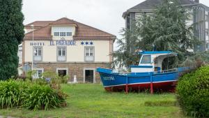 un barco azul sentado en el césped frente a un edificio en Hotel El Parador en Soto del Barco