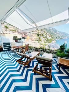 balcone con sedie, tavoli e vista sull'oceano di Villa Diamond Luxury Suite a Positano