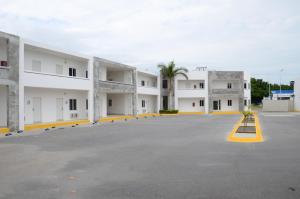 un gran aparcamiento con edificios blancos con acentos amarillos en HOTEL MONARCA, en Ciudad Victoria